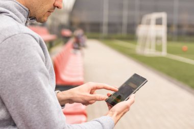 Yakışıklı, gülümseyen sakallı bir adamın portresi bahisçilerin mobil uygulamasını kazanmaktan mutlu oluyor. En sevdiği futbol takımına, arka plandaki stadyuma bahis oynadıktan sonra..