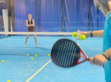 Bir koç olarak Padel tenis eğitimini güçlendirmek, sahadaki genç bir kadına ustalıkla eğitim verir, beceri geliştirmeyi teşvik eder ve olumlu bir öğrenme ortamı sağlar. Yüksek kalite fotoğraf