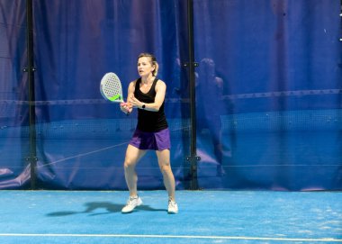  Bir kadın Padel oynuyor, açık mavi bir sahada topa vuruyor. Yüksek kalite fotoğraf