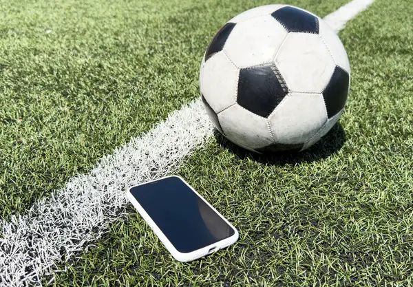 Adam cep telefonu kullanıyor, arka plan olarak futbol sahasını bulanık gösteriyor. Yüksek kalite fotoğraf