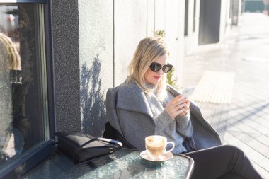 Genç ve güzel bir kadın bir kafede oturup cappuccino içiyor. Yüksek kalite fotoğraf