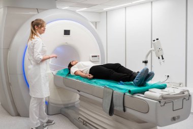 Modern hastane laboratuvarında bir hastaya tıbbi tomografi ya da MRI taraması yapın. Radyografi bölümünün içi. Beyaz odada teknolojik olarak gelişmiş ekipmanlar var. Manyetik rezonans tanılama makinesi.