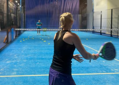Bir koç olarak Padel tenis eğitimini güçlendirmek, sahadaki genç bir kadına ustalıkla eğitim verir, beceri geliştirmeyi teşvik eder ve olumlu bir öğrenme ortamı sağlar. Yüksek kalite fotoğraf