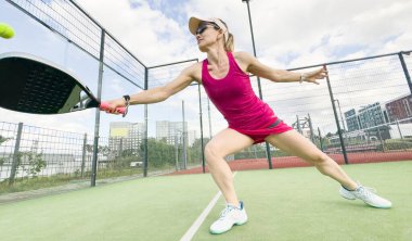 Tenis kulübünün açık hava kortunda Padel Tenis oynayan genç bir bayan. Yüksek kalite fotoğraf