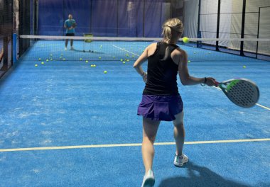  Bir kadın Padel oynuyor, açık mavi bir sahada topa vuruyor. Yüksek kalite fotoğraf