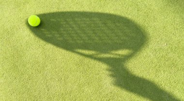 Yeşil çimlerin üzerinde sarı bir top olan padel raketinin gölgesi. Yüksek kalite fotoğraf
