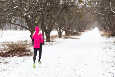 Açık hava spor egzersizleri, spor kıyafetleri fikirleri. Sıcak spor giysili bir kadın kış boyunca dışarıda koşuyor. Yüksek kalite fotoğraf