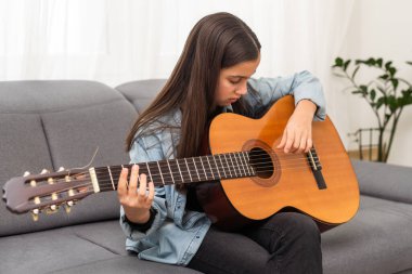 Güzel genç bir kız evde gitar çalar. Yüksek kalite fotoğraf