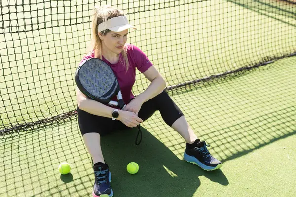 stock image Sporty european woman padel tennis player trains on the outdoor court using a racket to hit the ball. High quality photo