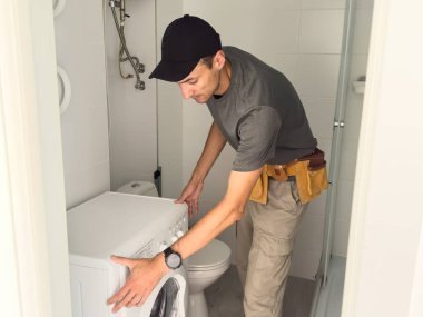 Tesisatçı beyaz arka planda çamaşır makinesini tamir ediyor. Yüksek kalite fotoğraf