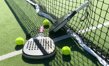 Padel tenis raketinin yanındaki çimenlikte sarı toplar açık havada, yeşil sahada, doğal ışıklandırmayla. Kürek bir raket oyunudur. Fotokopi alanı olan profesyonel spor konsepti. Yüksek kalite fotoğraf