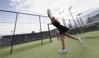 Açık kortta raketle padel oynayan genç ve sportif bir kız. Yüksek kalite fotoğraf