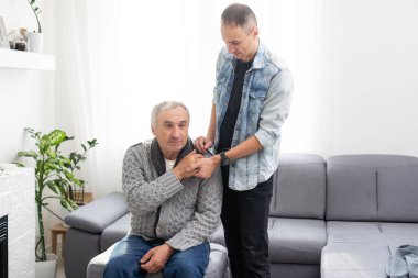 Yakışıklı, gülümseyen yetişkin bir adam yaşlı, olgun bir babaya sarılıyor, kameraya bakıyor. Mutluluk, sevgi ve ilgi. İki nesildir aile portresi çekiliyor. Babalar Günü konsepti. Yüksek kalite fotoğraf