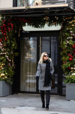 Muhteşem bir sarışın manken Noel tatilinde yerel alışveriş yapmak için sıcak bir günün tadını çıkarıyor. Yüksek kalite fotoğraf