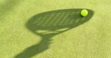 Yeşil çimlerin üzerinde sarı bir top olan padel raketinin gölgesi. Yüksek kalite fotoğraf