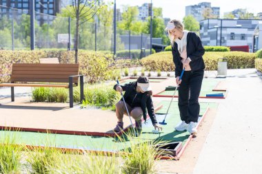 Anne ve kızı mini golf oynuyor, çocuklar yaz tatilinin tadını çıkarıyor. Yüksek kalite fotoğraf