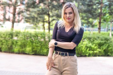 Genç sarışın kadın caddede kendine güvenen bir şekilde gülümsüyor. Yüksek kalite fotoğraf