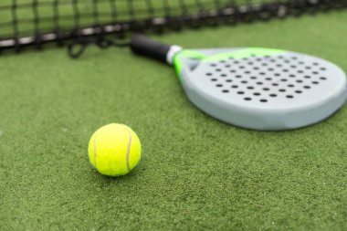 Padel raket ve padel topu gün batımında yeşil bir kortta. Yüksek kalite fotoğraf