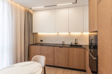 Lüks stüdyo dairede, aydınlık oturma odasının modern iç mekanı. Tahta masa ve siyah sandalyeler. Yüksek kalite fotoğraf