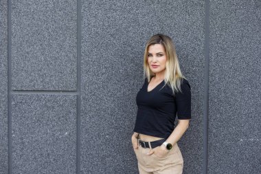 Genç sarışın kadın caddede kendine güvenen bir şekilde gülümsüyor. Yüksek kalite fotoğraf