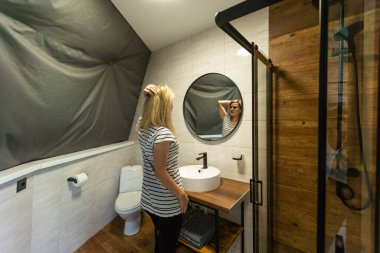 Kadın model, aynadaki yansımaya bakarak tenine dokunuyor. Gülümseyen kadın şımartıyor, sağlıklı nemlendirilmiş cilt bakımı, yaşlanan güzellik, cilt bakımı kozmetik konsepti