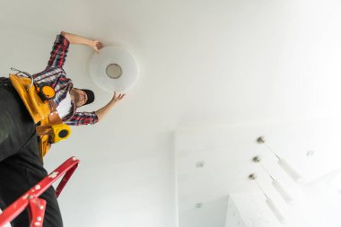 Bir elektrikçi tavana bir avize yerleştirir. Lambayı tavana takıp bağlayan bir elektrikçinin elleri. Yüksek kalite fotoğraf