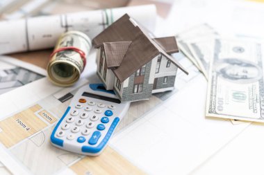 white metal model house with calculator and plans of building on white table with euro banknotes. costs of building a house. taking a loan. High quality photo clipart