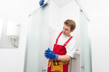 Genç adam banyoda duş kabinin kapısı tamiri
