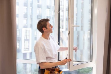 Yeni dairenin camlarını tamir eden bir tamirci.
