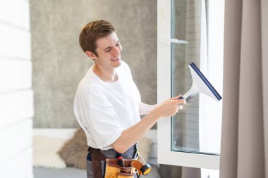 Ofisin camlarını temizleyen genç adam..