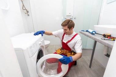 tesisatçı ev yapımı çamaşır makinesini tamir ediyor.