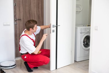 İç kapıların delinmesi ve kurulumu, zanaatkar kapı çerçevesinde el matkabı, kapı ve kurulum ile bir delik açar.