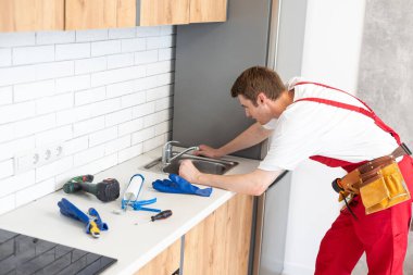 Genç tamirci mutfak lavabo musluk mutfak Room yükleme.