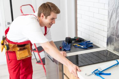 craftsman installs hob in kitchen. Household Appliance Installation Services Concept