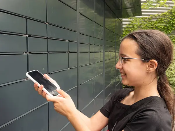 Genç kız akıllı telefondan posta teslimatını açıyor. Terminal makinası ve paket teslimatı. Yüksek kalite fotoğraf