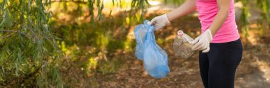 Genç bayan gönüllü olarak parktaki çöpleri topluyor. Çevre koruma kavramı.