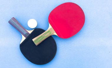 Arka planda masa tenisi raketleri ve mavi masada izole edilmiş beyaz top var. Üst Manzara. Yüksek kalite fotoğraf