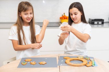 İki kız kardeş Noel kurabiyeleri yaptıktan sonra mutfakta oynuyorlar, masaya ve yüzlerine un çiziyorlar. Noel, yeni yıl konsepti. Yüksek kalite fotoğraf
