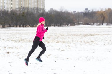 Açık hava spor egzersizleri, spor kıyafetleri fikirleri. Sıcak spor giysili bir kadın kış boyunca dışarıda koşuyor. Yüksek kalite fotoğraf