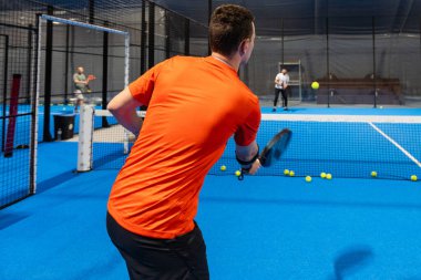 Padel oyuncusunun Padel 'i kapalı bir sahada, kalenin arkasında oynadığı bilinmiyor. Yüksek kalite fotoğraf