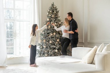 Mutlu Noeller ve mutlu tatiller. Anne, baba ve çocuk hediye değiş tokuşu. Ebeveynler ve kızları kapalı alanda eğleniyorlar. Odada hediyeleri olan sevgi dolu bir aile. Yüksek kalite fotoğraf