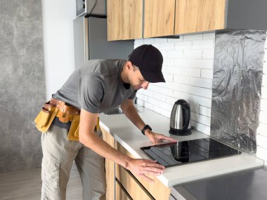  Üniformalı bir görevli mutfakta indüksiyon sobasını tamir ediyor. Yüksek kalite fotoğraf