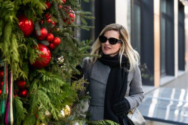 Muhteşem bir sarışın manken Noel tatilinde yerel alışveriş yapmak için sıcak bir günün tadını çıkarıyor. Yüksek kalite fotoğraf