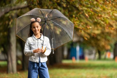 Kid playing out in the rain. Children with umbrella play outdoors in rain. autumn weather
