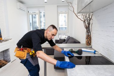 Zanaatkar mutfağa hob kuruyor. Ev Aletleri Kurulum Hizmetleri Konsepti. Yüksek kalite fotoğraf