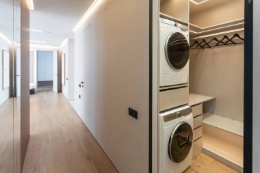 a laundry room with washer, dryer and washing machine on the wall in front of the closet door. High quality photo clipart