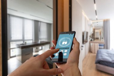 Akıllı ev otomasyon uygulaması arka planda iç mekan olan kadın eliyle akıllı telefondan tutulmuş. Yüksek kalite fotoğraf
