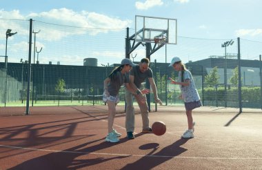 Bir spor ailesi basketbol oynar, genç bir baba, kızlar basketbol sahasında boş zaman geçirir, sağlıklı bir hayat sürer, genç bir kız top atar. Yüksek kalite fotoğraf