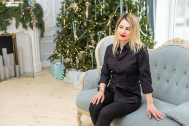 Noel iç tasarımlı bir kadın, ışıklarla süslenmiş Xmas ağacı oyuncaklar, mumlar, fenerler, şöminenin içindeki çelenk ışıkları. Yüksek kalite fotoğraf