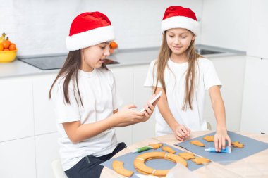 Çocuklar Noel kurabiyelerini masaya dekore ettiler. Yüksek kalite fotoğraf